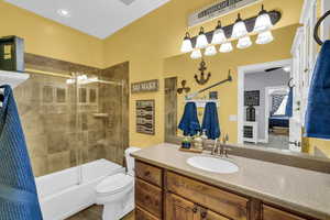 Full bathroom featuring tile patterned flooring, bath / shower combo with glass door, vanity, and toilet