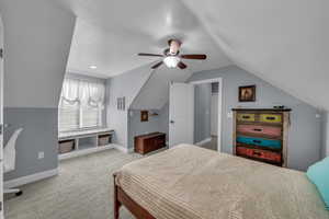 Bedroom with ceiling fan, lofted ceiling, and light colored carpet