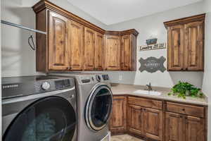 Laundry area with sink, washing machine and dryer, cabinets, and light tile patterned flooring