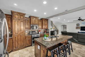 Kitchen with sink, a breakfast bar area, appliances with stainless steel finishes, tasteful backsplash, and an island with sink