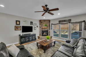 Living room with a stone fireplace and ceiling fan