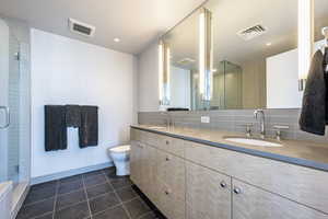 Bathroom with backsplash, tile patterned flooring, vanity, an enclosed shower, and toilet