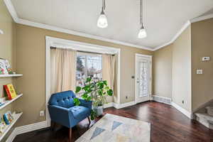 Foyer entrance with crown molding and dark hardwood / wood-style floors