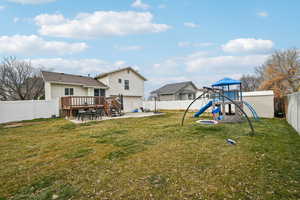 Exterior space with a wooden deck, a patio area, and a playground