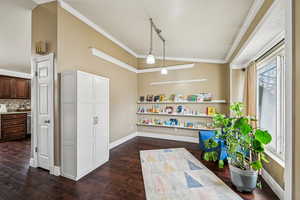 Interior space with dark wood-type flooring, lofted ceiling, and ornamental molding