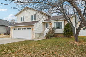 Tri-level home featuring a garage and a front yard