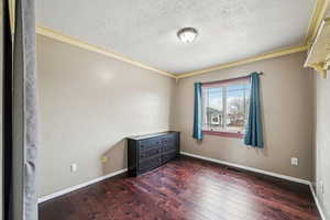 Unfurnished room featuring crown molding, dark hardwood / wood-style flooring, and a textured ceiling