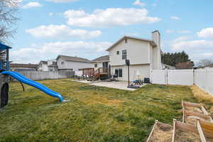 Back of house featuring a playground, a patio, a yard, and a deck