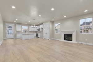 Unfurnished living room with plenty of natural light, sink, and light wood-type flooring