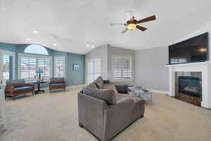 Living room featuring a premium fireplace, lofted ceiling, plenty of natural light, and light carpet