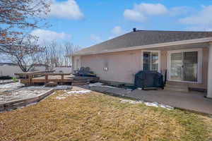 Rear view of house featuring a deck, a patio area, and a lawn