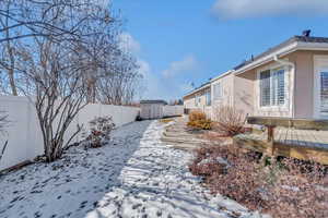 Yard layered in snow with a storage shed and a deck