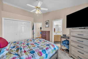 Bedroom featuring ensuite bathroom, light carpet, ceiling fan, and a closet