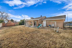 Back of house featuring a yard, a patio, and a playground