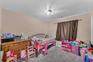 Bedroom with light carpet and a textured ceiling