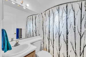 Full bathroom with vanity, shower / bathtub combination with curtain, and toilet