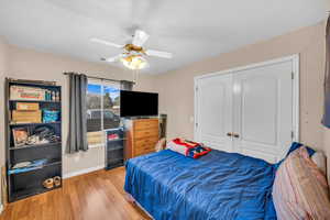 Bedroom with light wood-type flooring, ceiling fan, and a closet