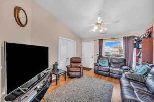 Living room with light hardwood / wood-style flooring, ceiling fan, and vaulted ceiling