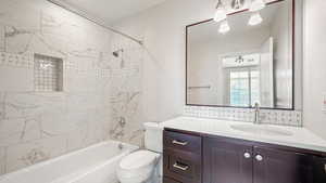 Full bathroom featuring vanity, decorative backsplash, toilet, and tiled shower / bath combo