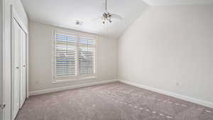 Empty room featuring vaulted ceiling, carpet flooring, and ceiling fan