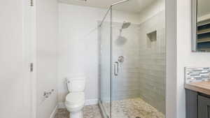 Bathroom with vanity, toilet, a shower with shower door, and backsplash