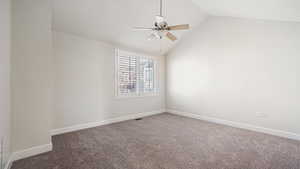 Empty room featuring ceiling fan, carpet flooring, and vaulted ceiling