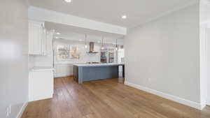 Bar with sink, tasteful backsplash, decorative light fixtures, ventilation hood, and white cabinets