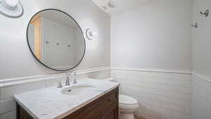 Bathroom with vanity, tile walls, and toilet