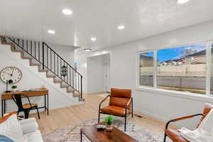 Living room featuring crown molding, a textured ceiling, and light wood-type flooring