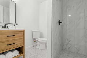 Bathroom with tile patterned floors, vanity, toilet, and a tile shower