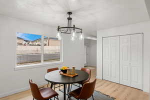 Dining room with ornamental molding, light wood-type flooring, and a textured ceiling