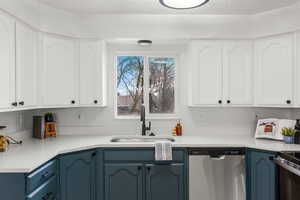 Kitchen featuring sink, stainless steel dishwasher, white cabinets, and blue cabinets