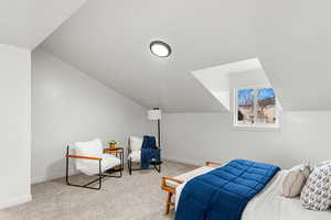 Bedroom with vaulted ceiling and light carpet