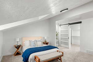 Bedroom with carpet floors, a barn door, and a textured ceiling