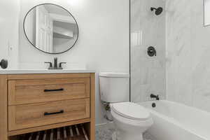 Full bathroom with vanity, tiled shower / bath combo, and toilet