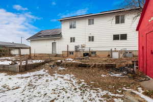 Snow covered back of property featuring solar panels