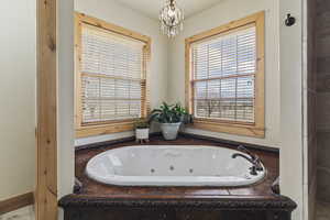 Bathroom with a chandelier and tiled tub