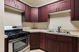 Kitchen with gas range, sink, and light tile patterned flooring