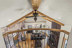 Interior details with beamed ceiling, wood-type flooring, and ceiling fan with notable chandelier