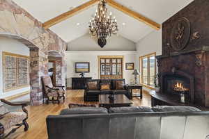 Living room featuring lofted ceiling with beams, a fireplace, and light hardwood / wood-style floors