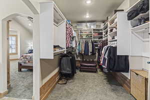 Spacious closet featuring lofted ceiling, carpet flooring, and ceiling fan