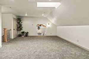 Bonus room featuring ceiling fan, lofted ceiling with skylight, and carpet