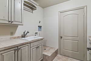 Clothes washing area featuring cabinets, sink, and washer hookup