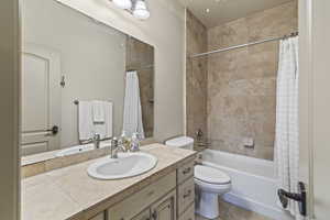 Full bathroom featuring vanity, shower / bath combination with curtain, and toilet