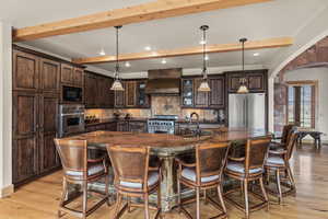 Kitchen with high quality appliances, premium range hood, decorative backsplash, and decorative light fixtures