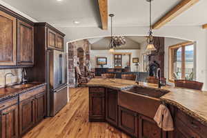 Kitchen with high end fridge, sink, pendant lighting, and dark brown cabinets