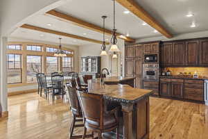 Kitchen with pendant lighting, black microwave, oven, a kitchen breakfast bar, and a spacious island