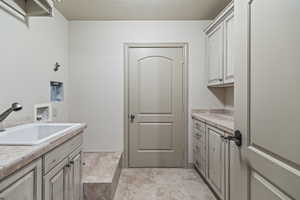 Clothes washing area with cabinets, hookup for a washing machine, and sink