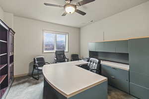 Home office featuring dark carpet and ceiling fan