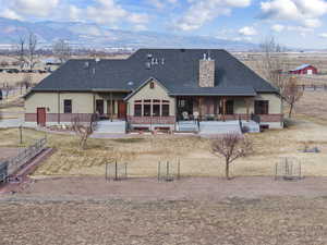 Rear view of property with a porch, a mountain view, and a lawn